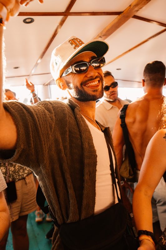 Stormy McGee grinning in sunglasses and a fitted cap at a boat party